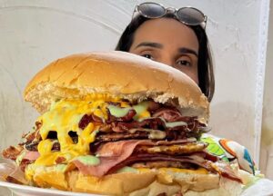 Suzanne Moraes, idealizadora da Feira Nacional do Podrão, com hambúrguer gigante da Esquenta Tia Suzy